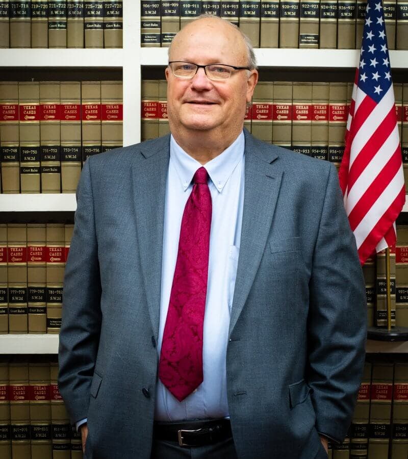 Attorney Ricky Richards standing in front of law books and US flag
