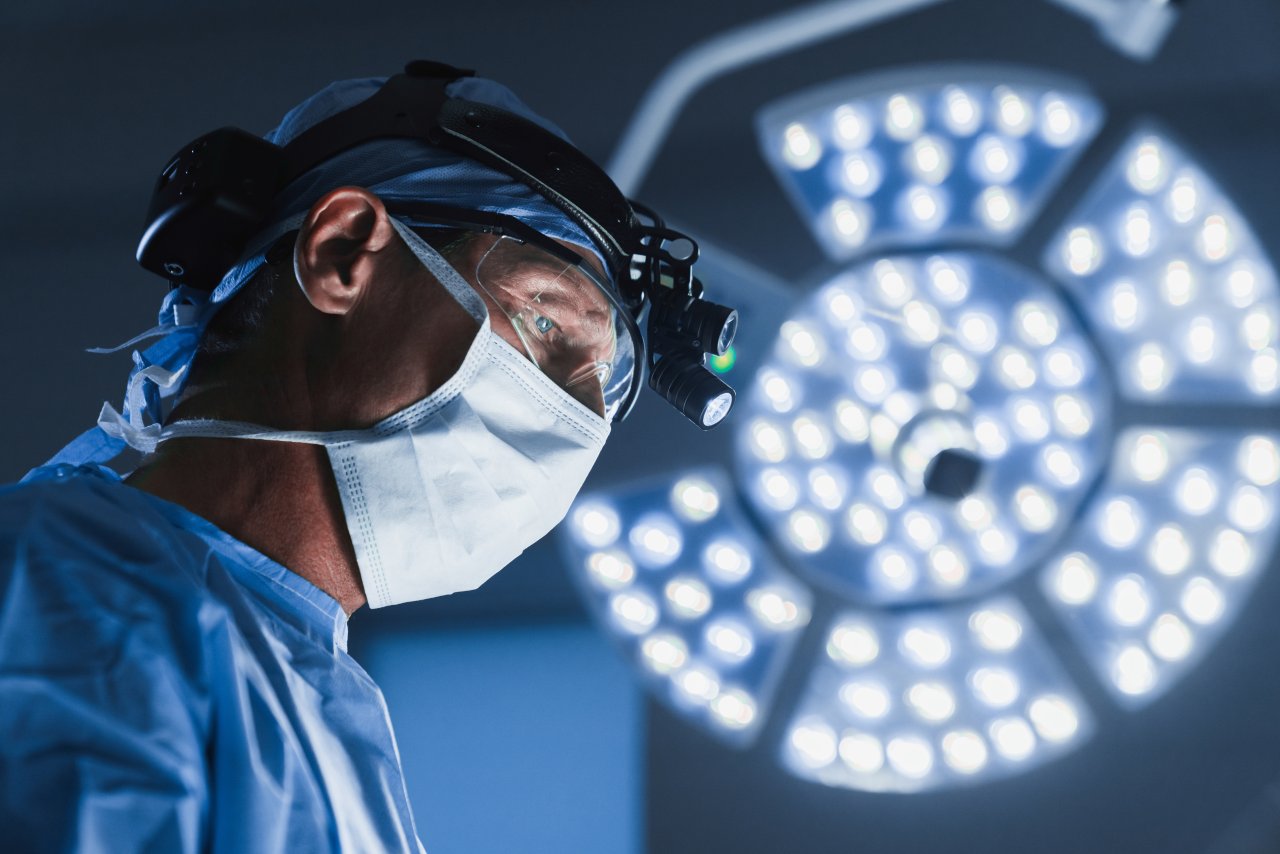 A surgeon performing surgery underneath a large surgical light