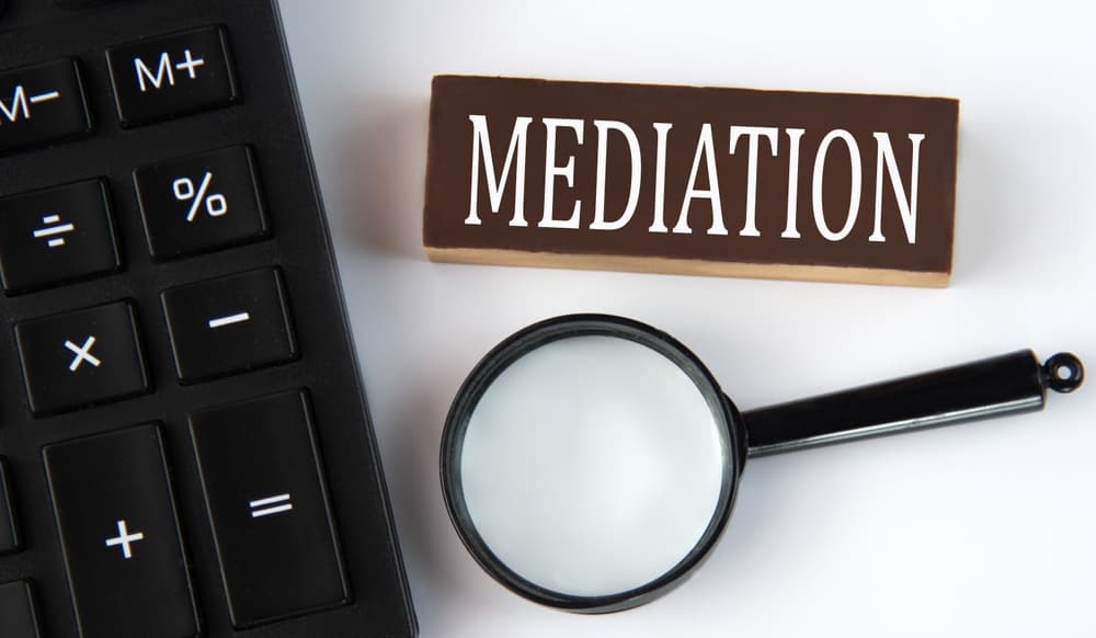 MEDIATION - word on a brown wooden block with a calculator