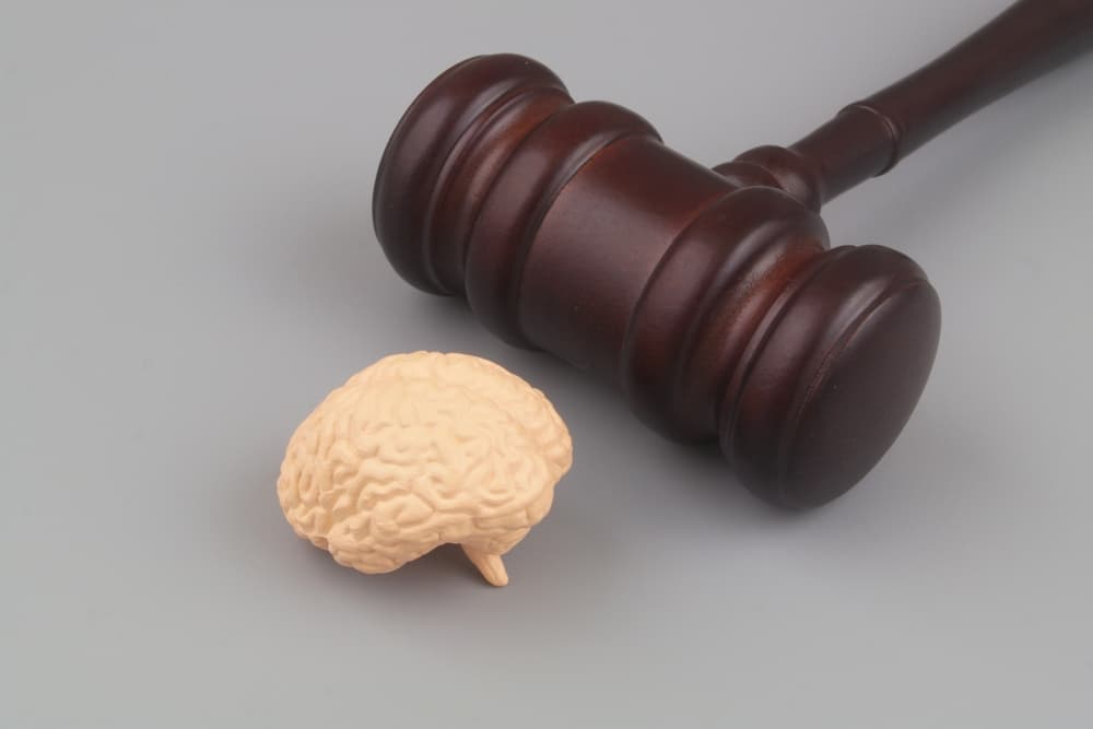 Human brain with wooden gavel on gray background.