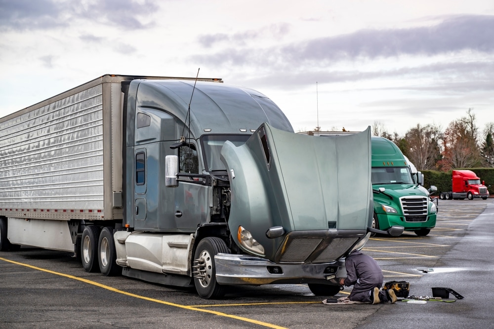 Damaged semi-truck with hood open being fixed, symbolizing the impact of truck accidents and the need for legal guidance.